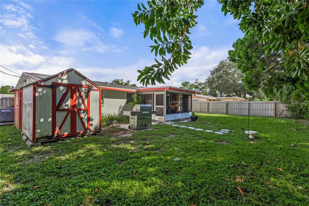 Spacious fully fenced-in back yard featuring a shed for extra storage.