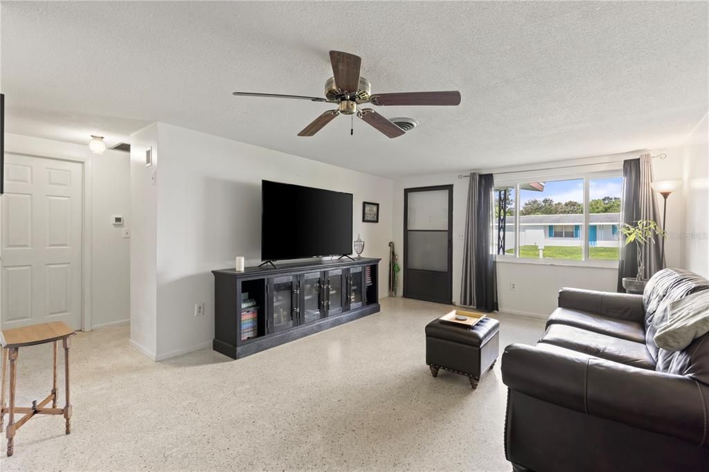 Living room featuring terrazzo floors, and large windows.