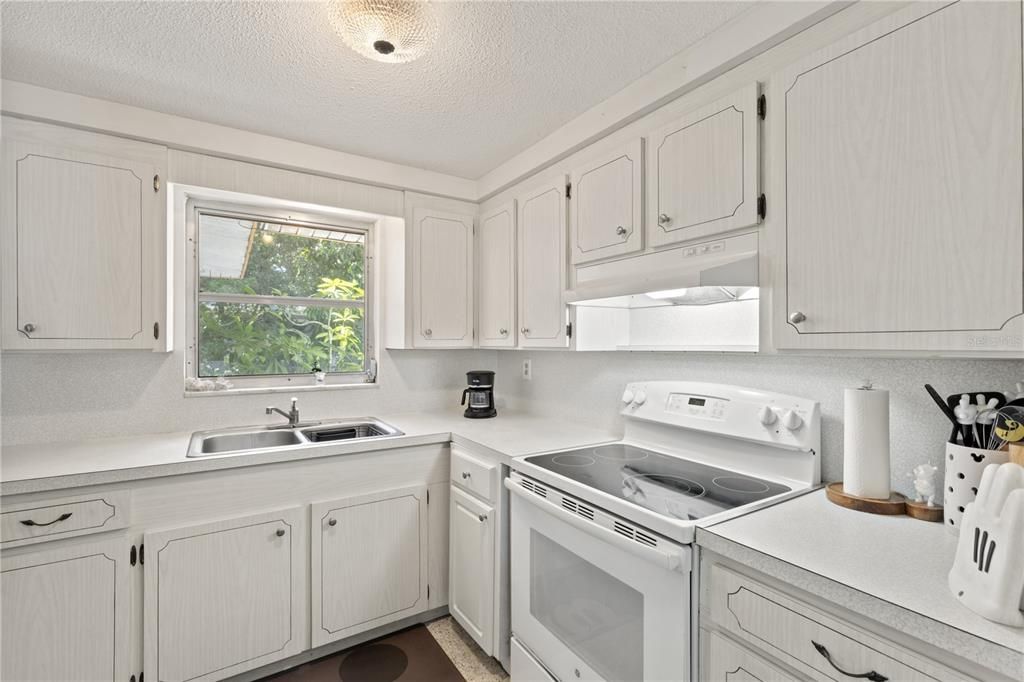 Galley style kitchen featuring ample cabinets, solid surface counter tops, and a garden window.