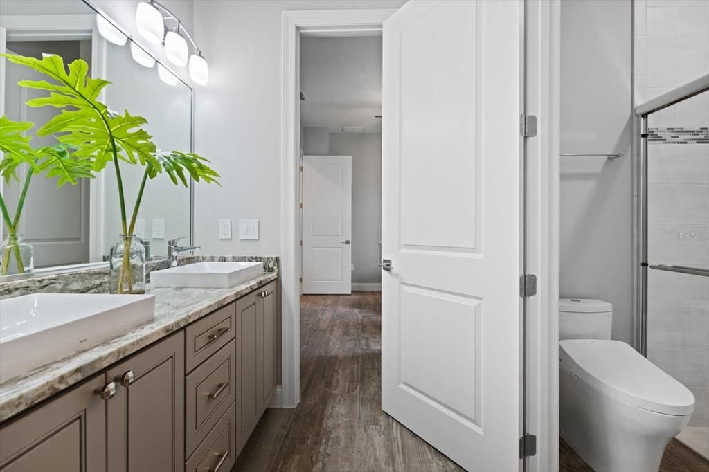 Jack and Jill bathroom with double vanities. Separate area with shower and commode