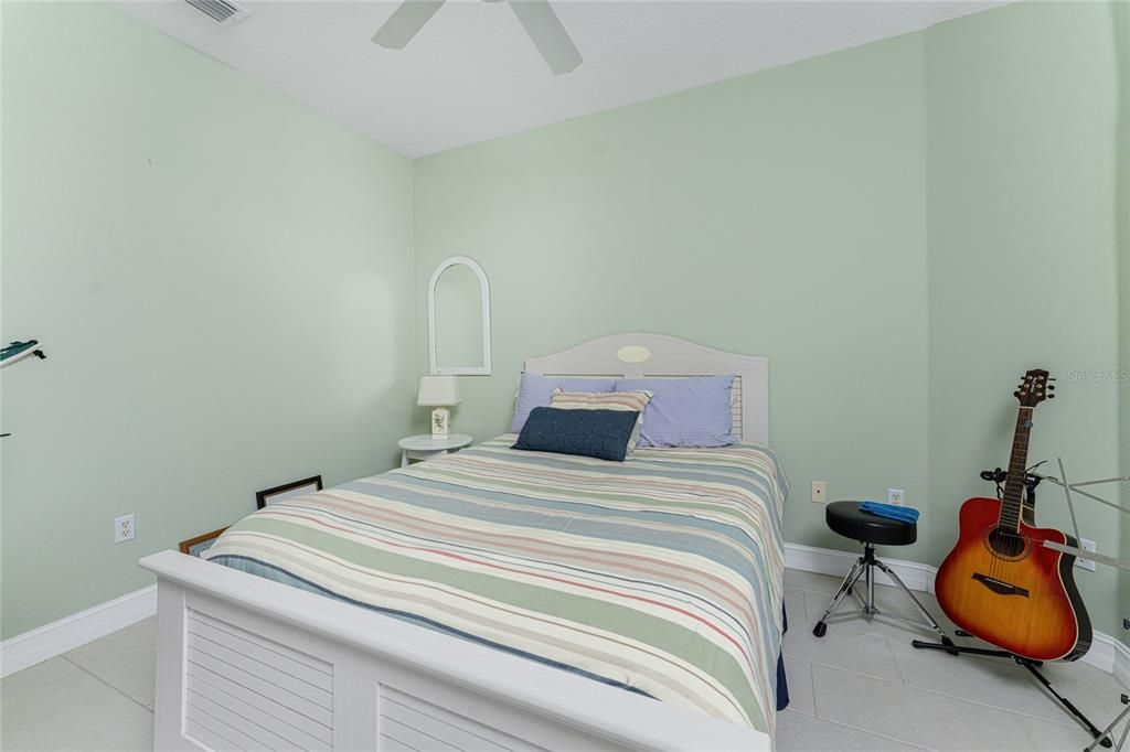 Welcoming second bedroom is enchanced with porcelain creme subway style flooring to match it tropical setting