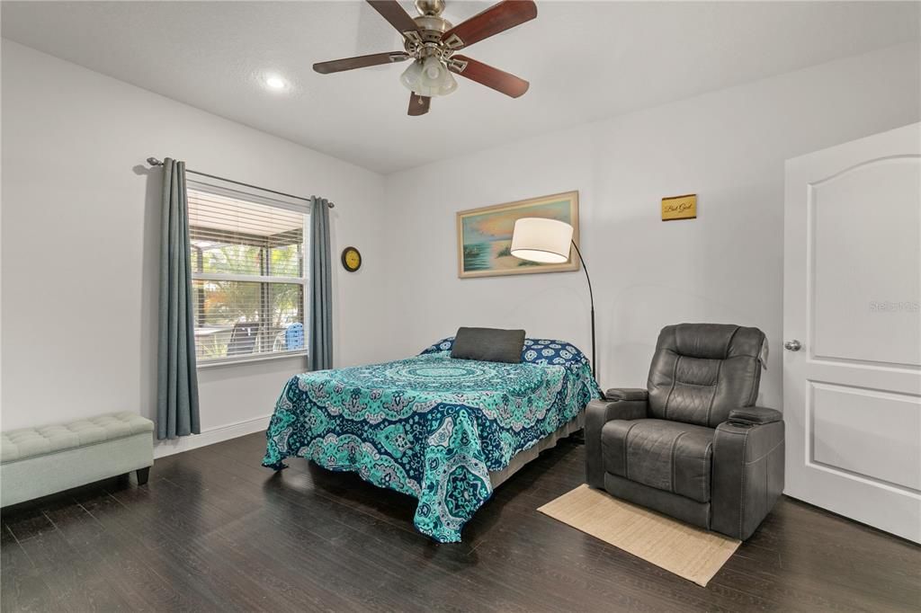 It could be a guest suite or In-laws retreat on the main floor. The 5th bedroom is approx 13'x15' with a sitting area, laminate flooring, 4 baseboards, a fan and blinds. The window looks out to the pool area.