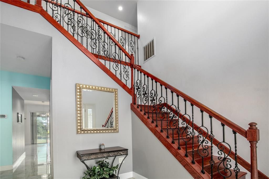 Let's head upstairs by way of this impressive staircase with decorative rod iron and wood railings.