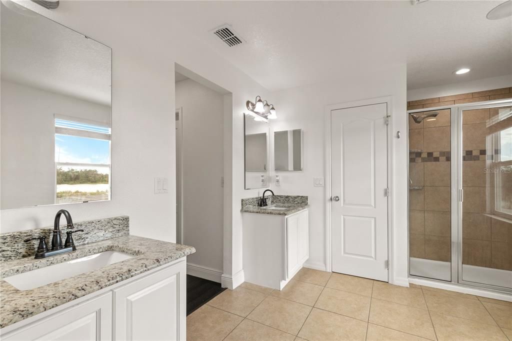 The Ensuite Bathroom has duel vanities with granite counters, a garden tub, a separate step-in tiled shower with rain head and a private water closet. Ceramic tile flooring continues in the wet areas of the home.