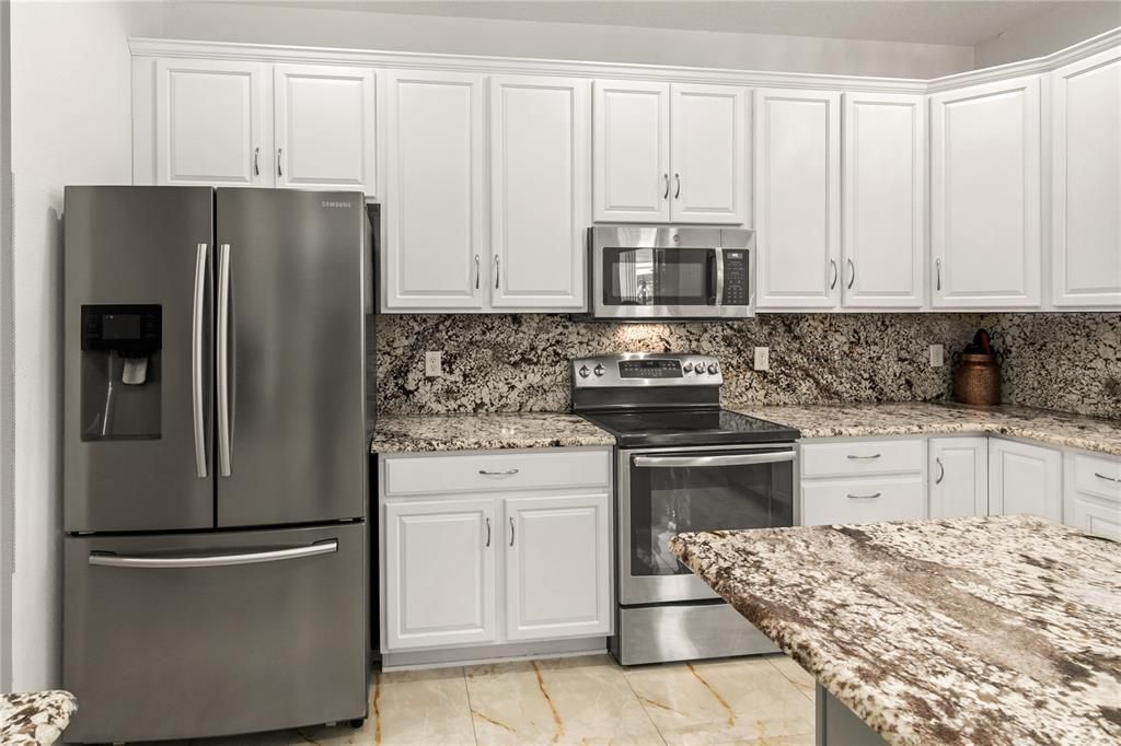 The stainless steel appliances include a Samsung double door refrigerator with ice maker and bottom freezer, a flat top range and microwave.