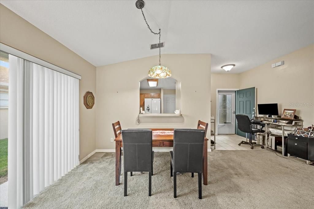 The dining room is filled with natural light from a sliding glass door that leads out to the side yard.