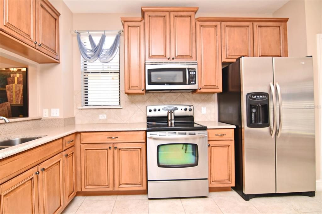 Lovely stacked cabinets with stainless steel appliances and solid surface counters.