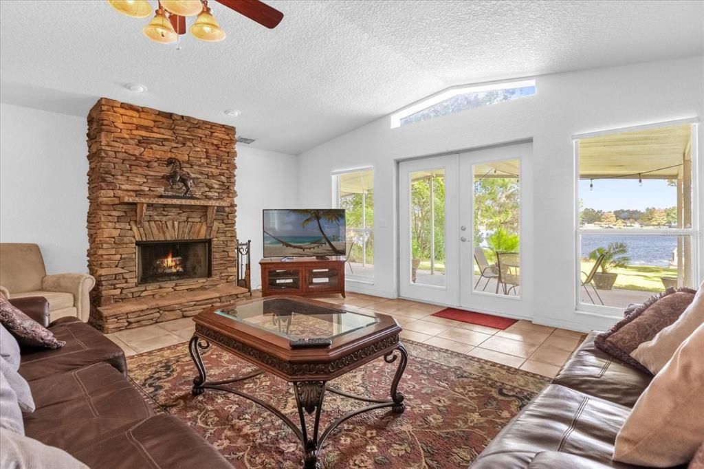 Large living room/family room with wood burning fireplace, vaulted ceilings and views of Lake Arnold!