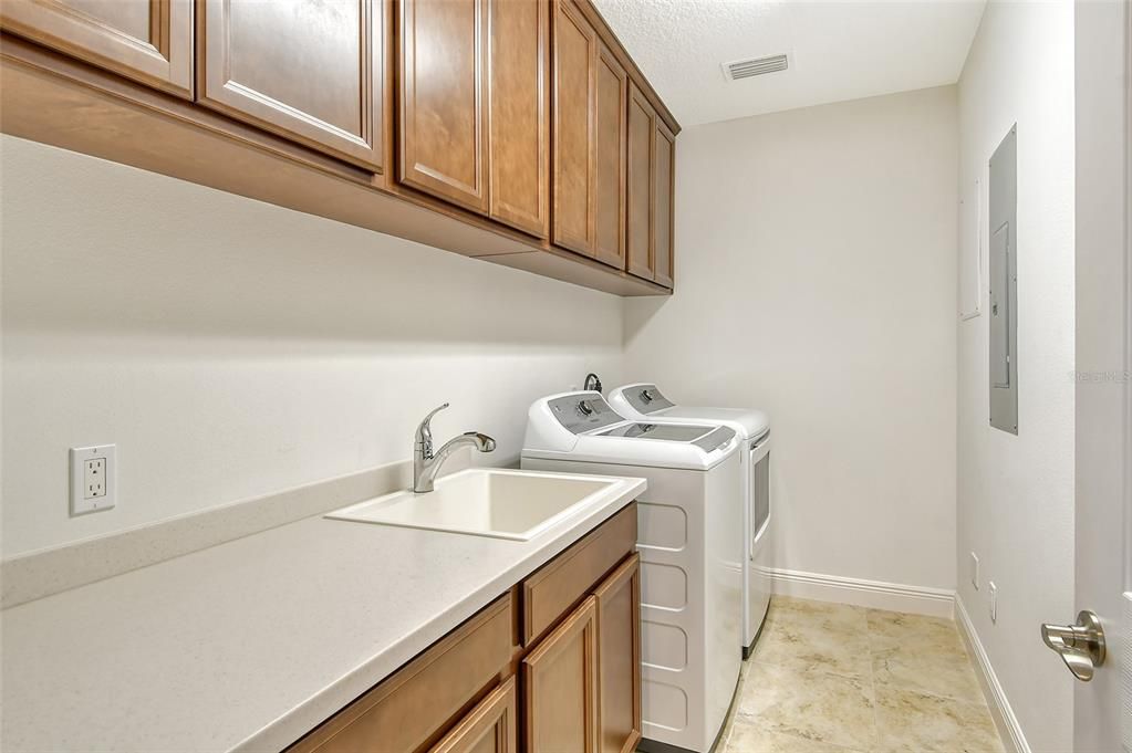 Laundry room with utility sink and plenty of cabinetry.