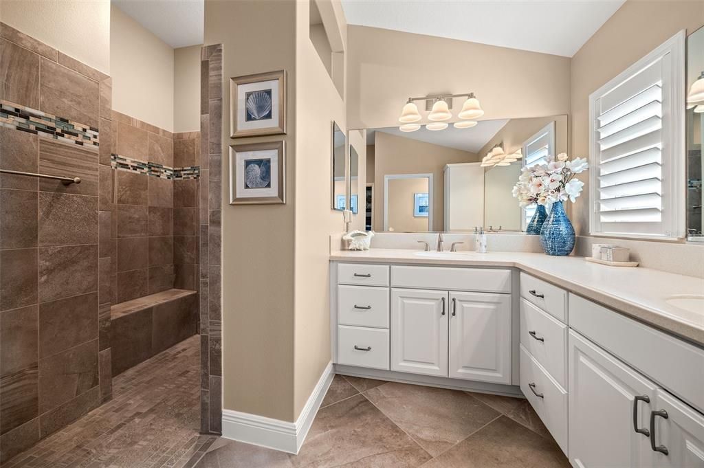 luxurious ensuite bathroom with dual sinks, a Roman shower, and a spacious walk-in closet.