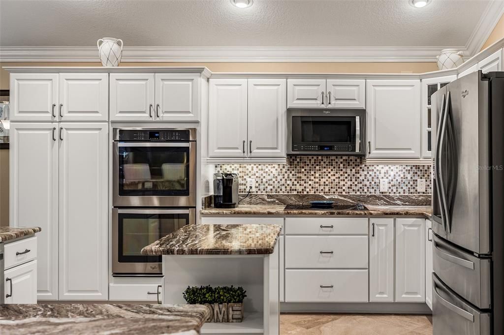 The kitchen boasts white shaker-style cabinetry with under and over-cabinet lighting