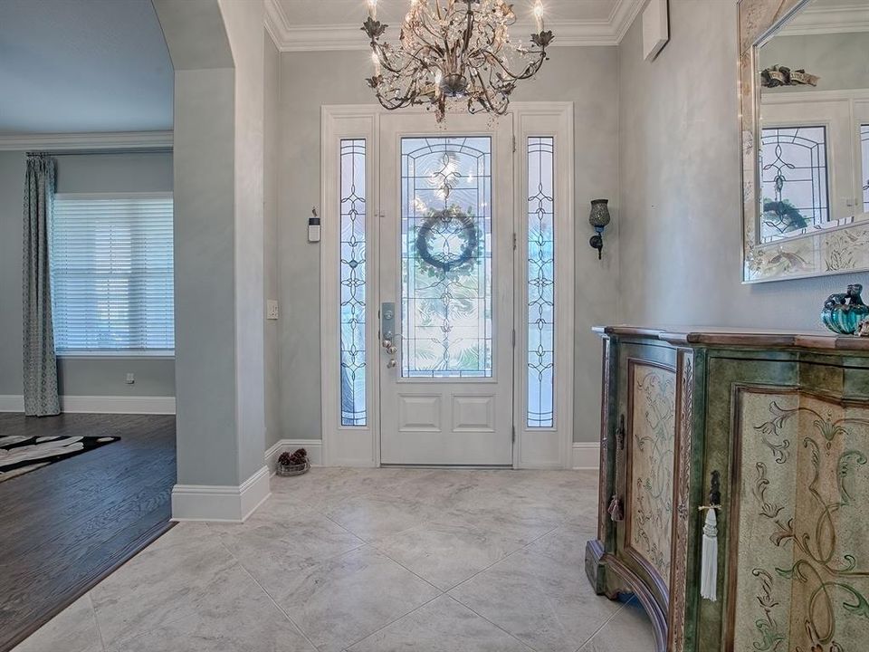 LOVELY ENTRANCE WITH LEADED GLASS FRONT DOOR WITH SIDELITES AND DIAGONAL TILE IN THE FOYER WITH CUSTOM CHANDELIER.