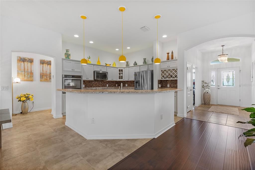 Tile in dining room and kitchen, laminate floors in living room, pendant lights over breakfast bar