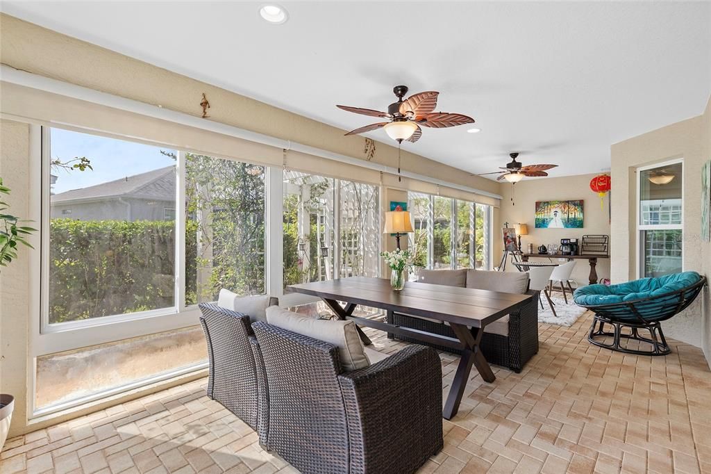 Enclosed lanai with double pane windows, brick paver flooring, two sets of sliding doors leading to outside area, one set of sliding doors leading to living room, one set of sliding doors leading to dining room