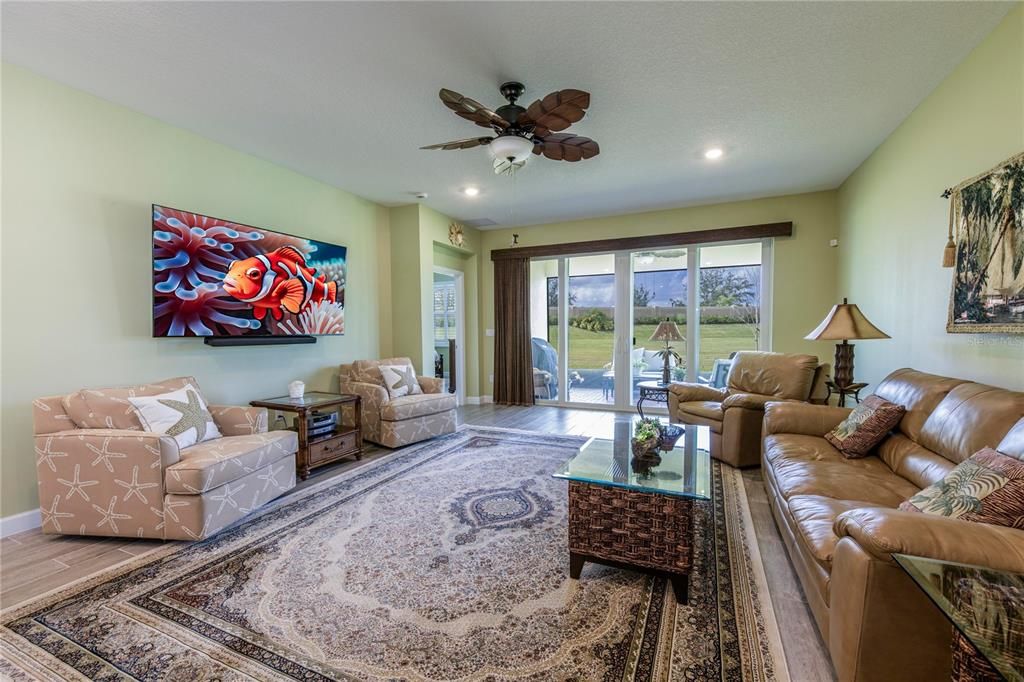 Living Room-Glass slider doors upgraded with a wood woven shade leading to screened in lenai, upgraded with a ceiling fan