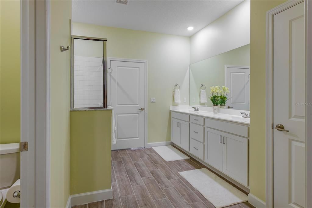 Primary Bathroom- private water closet (toilet), Clear Glass enclosed over-sized glass shower, linen closet