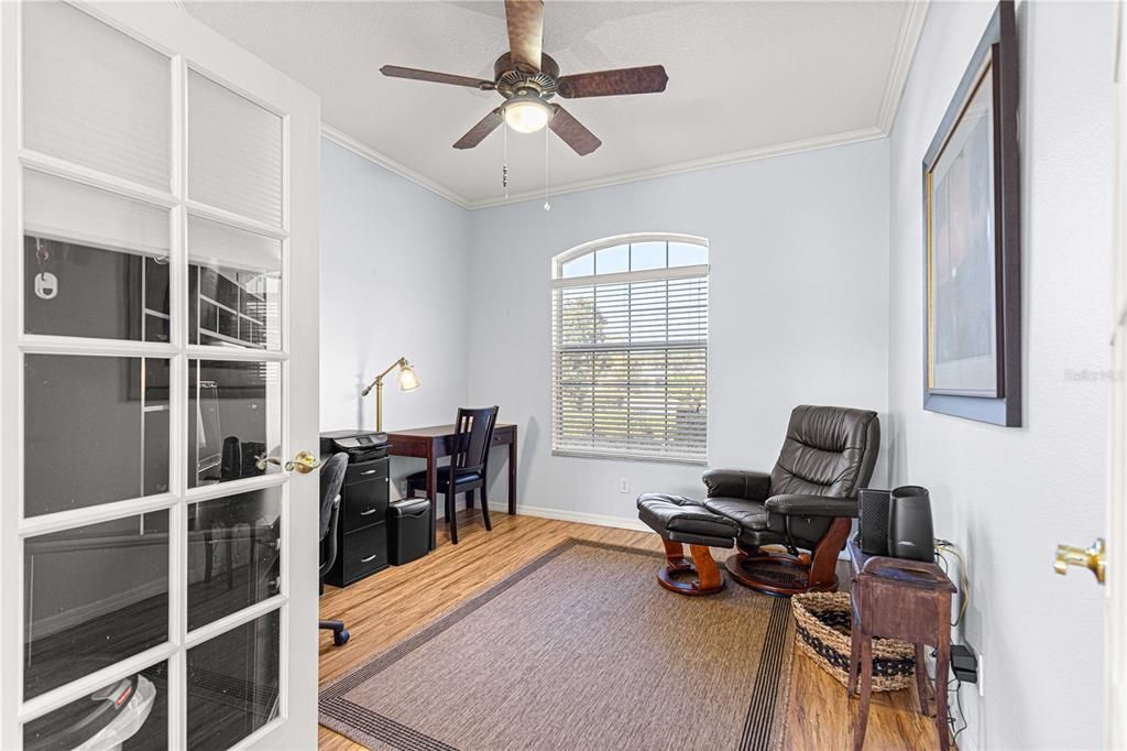 Den with Crown molding and wood flooring