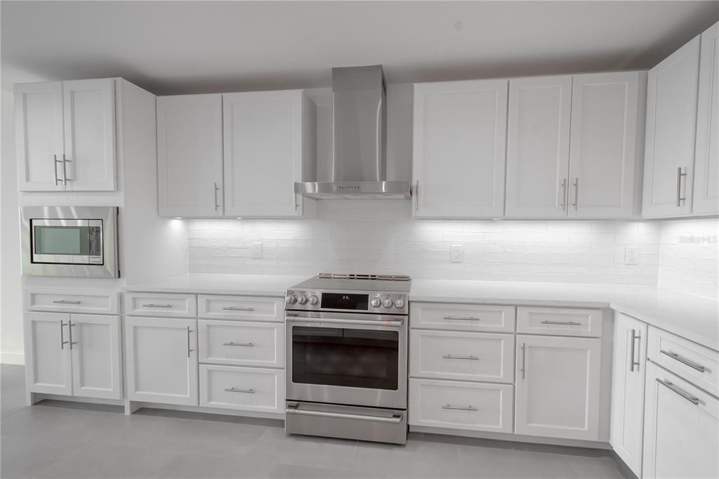 The kitchen boasts a stunning tile backsplash paired with sleek quartz countertops.