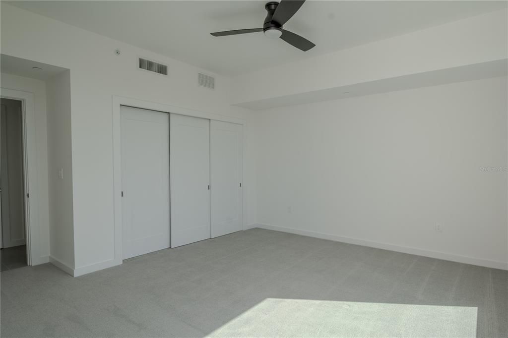 The 2nd bedroom features neutral tone carpet, a sleek ceing fan and a built-in closet.