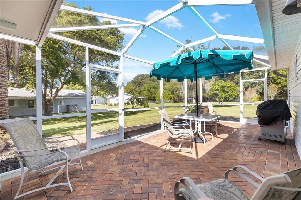 BRICK PAVED PATIO WITH SCREENED BIRDCAGE.