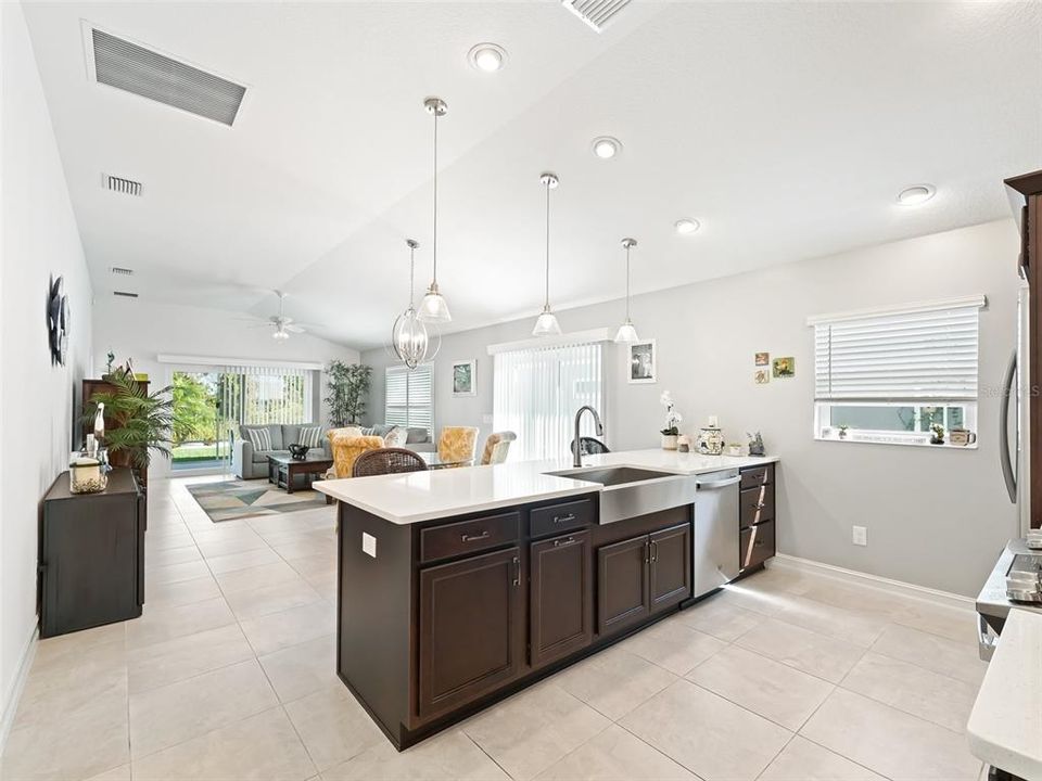 Kitchen open to the Dining and Living Area and featuring a large Island with Farmer Sink, Dishwasher and Quartz Countertops