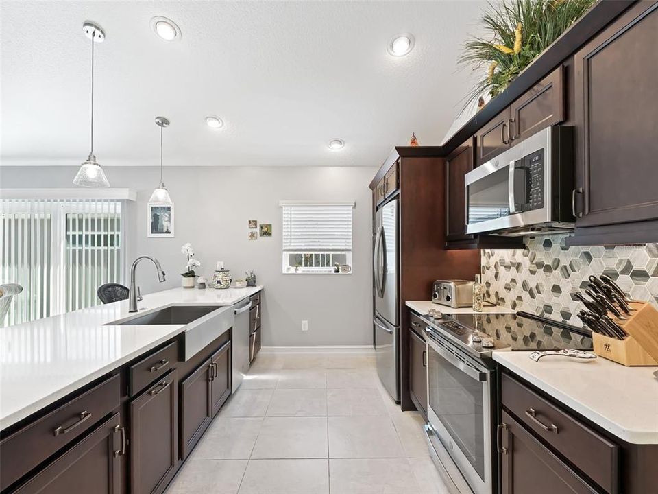 Bright and airy Kitchen open to the Dining and Living area.  Featuring Vaulted Ceilings, Wood Cabinetry, Quartz Countertops, Stainless Steel Appliances and Custom Tiled Backsplash