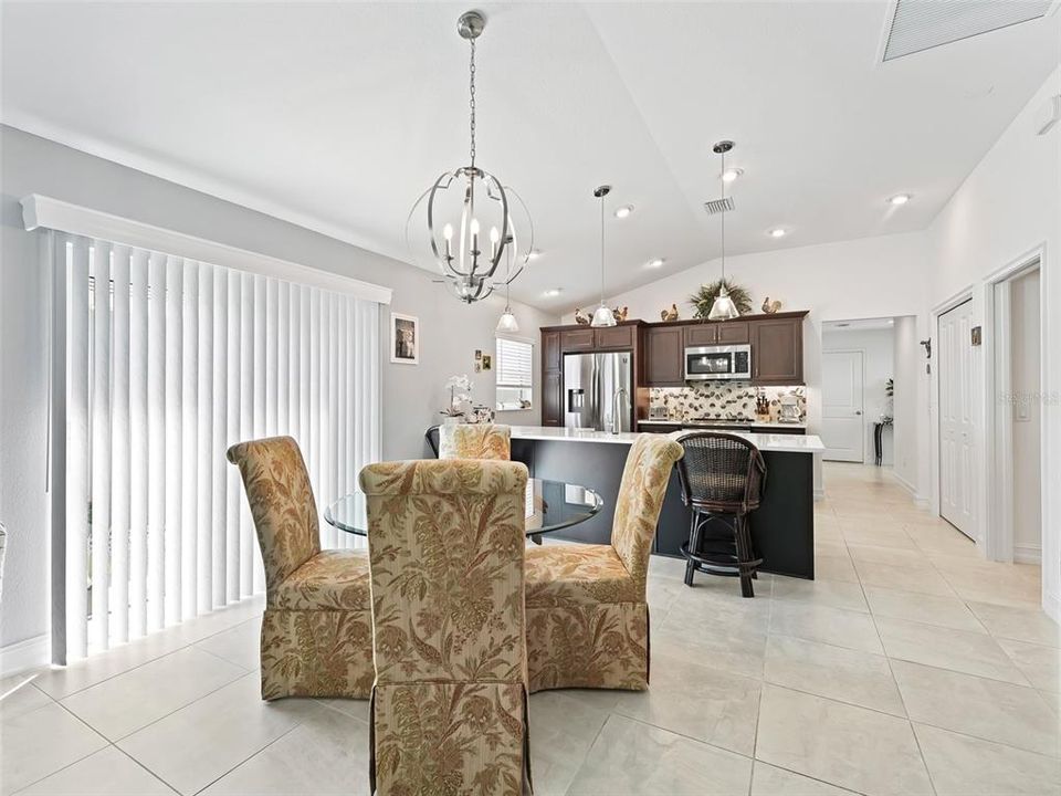 Dining area featuring Vaulted Ceilings and Sliding Glass Doors leading out to the side patio area