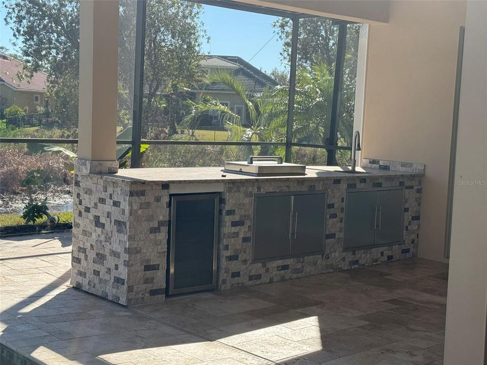 Outdoor kitchen with refrigerator and a television set.