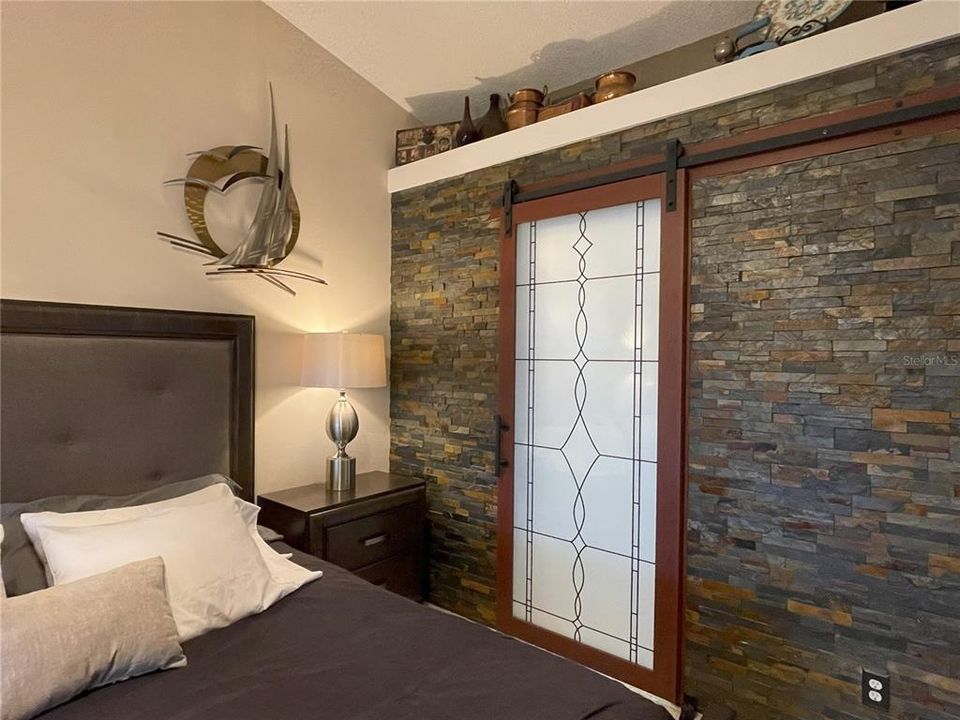 Stacked stone wall and glass barn door to bathroom