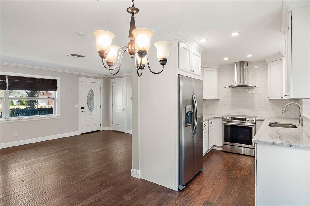 View from the dining and kitchen area looking toward the living room and front door.  Access to the laundry room and utility garage is to the right of the front door.