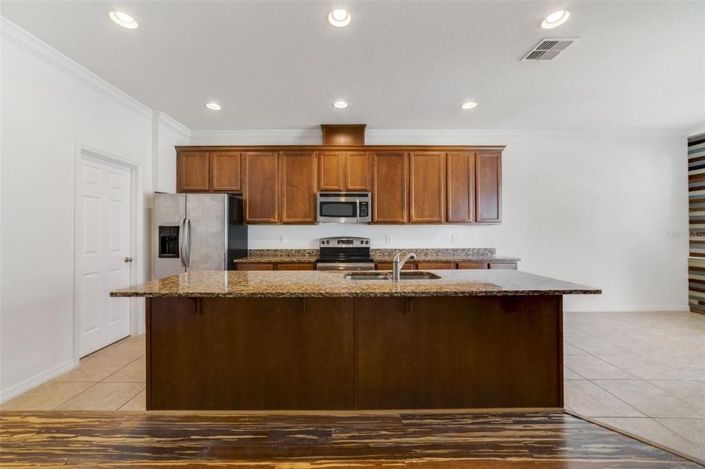 The kitchen is well appointed with STAINLESS STEEL APPLIANCES, granite counters, a large ISLAND and WALK-IN PANTRY...