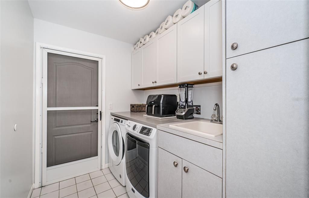 Indoor laundry room with sink and storage