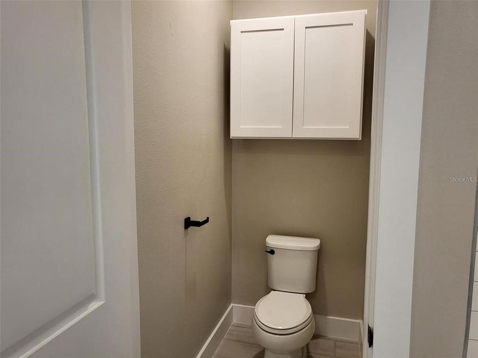 Private toilet area with cabinet above