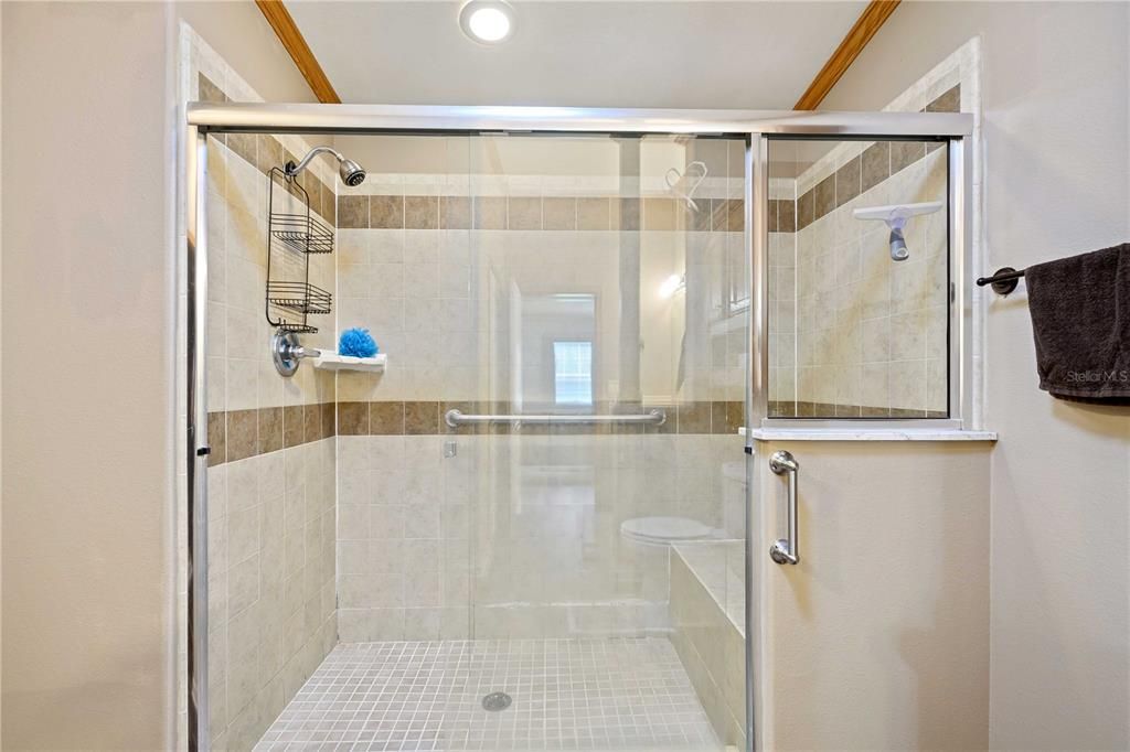 Shower is tiled with glass doors.