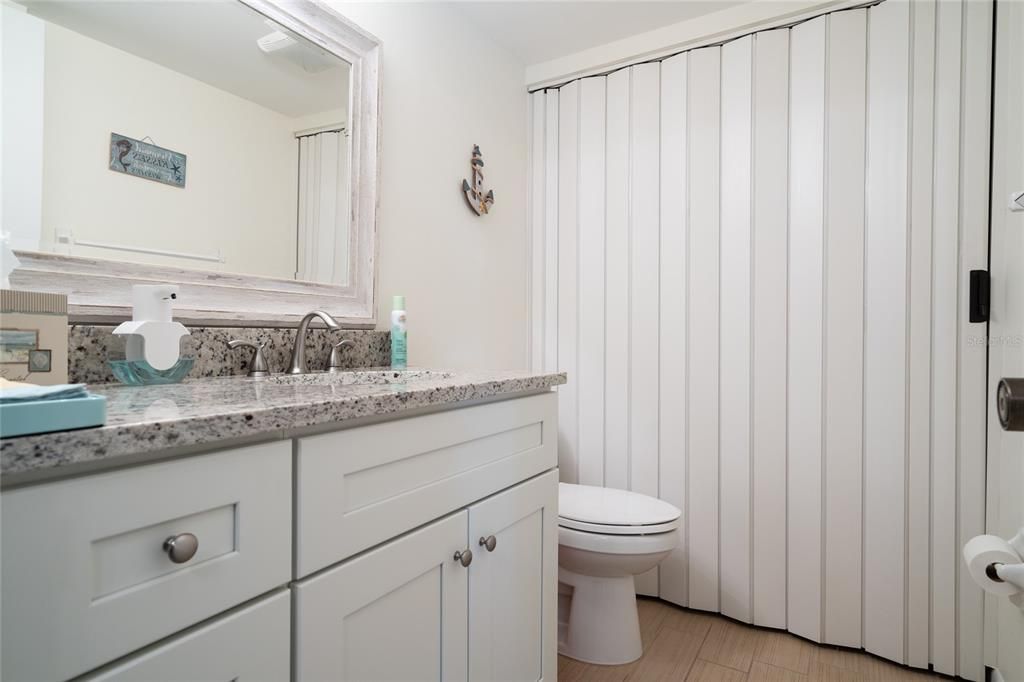 All baths, including this first floor bath, have granite topped, soft-close vanities. Laundry room afar.