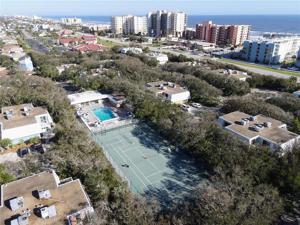 Overhead view of tennis/pickleball courts and community swimming pool. Notice the privacy of the trees in Bahamian Club.