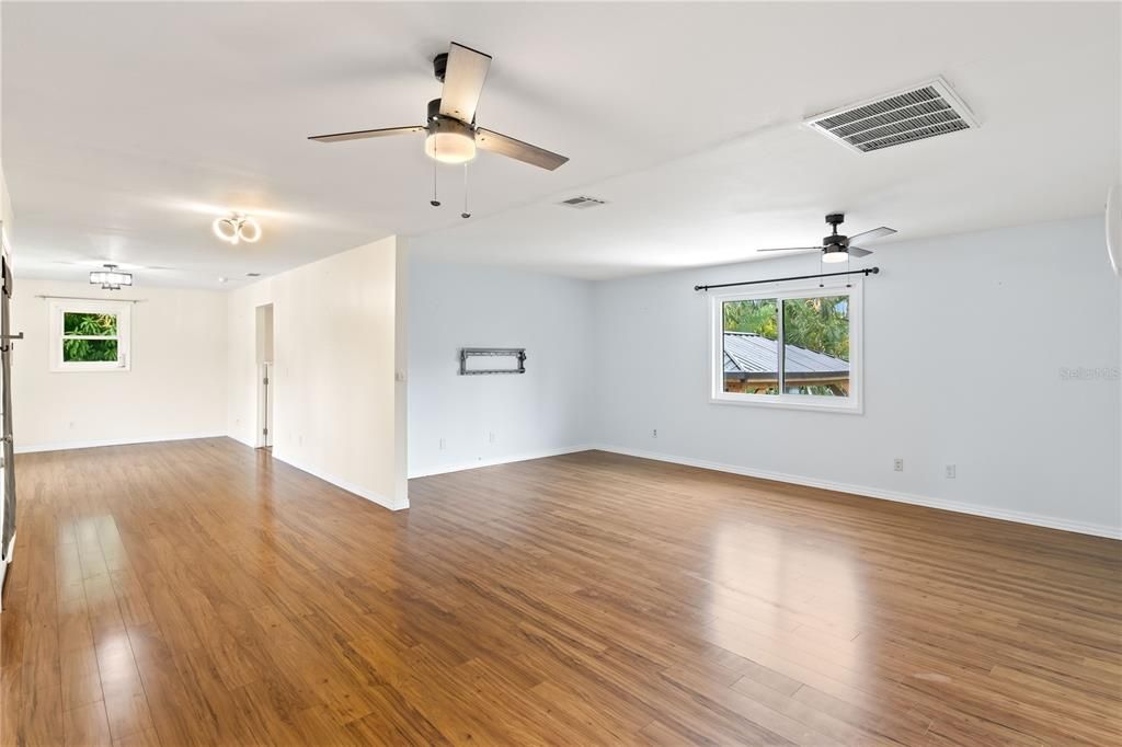 Large and bright living room and dining room featuring wood flooring and ceiling fans.