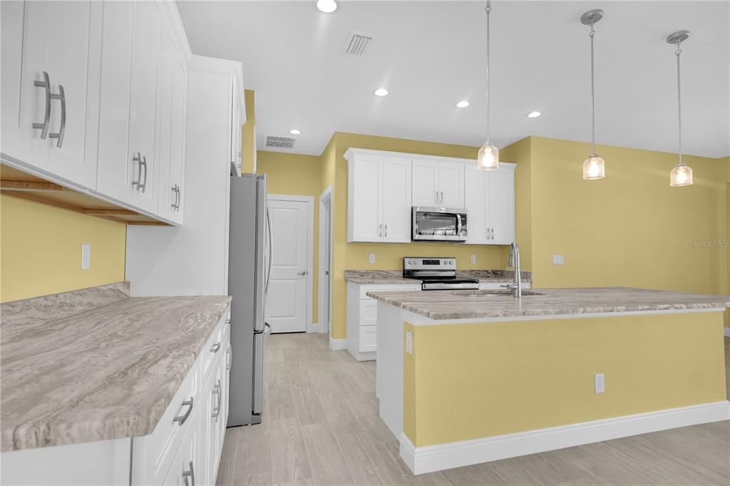 Kitchen Featuring Light Cabinetry and Custom Granite Counter Tops