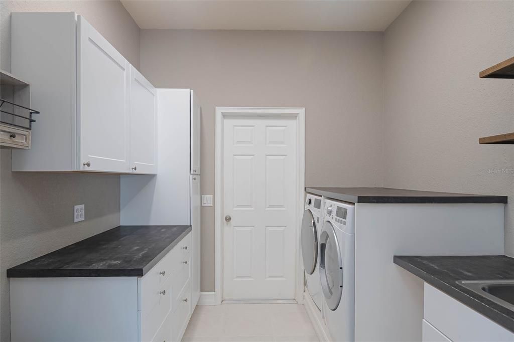 Laundry room with a laundry tub, and shelving just off the 2 car garage in the main home