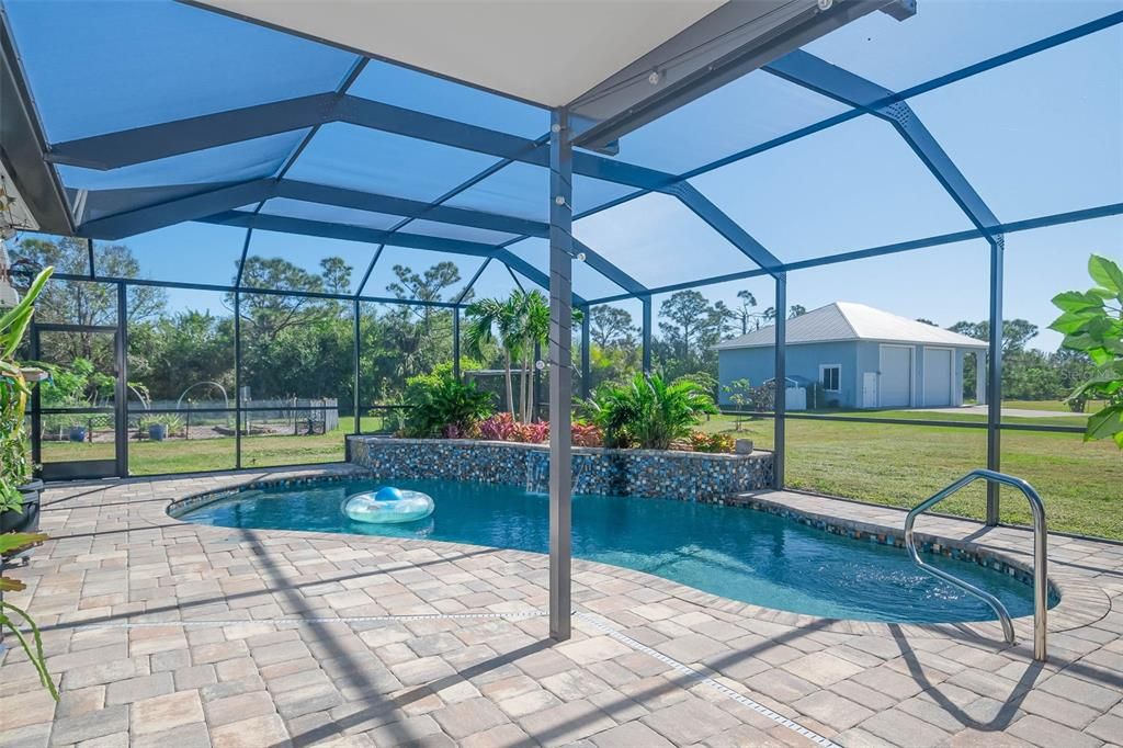 Mansard pool cage encloses the heated saltwater pool, complemented by a cascading waterfall and a beautifully landscaped area