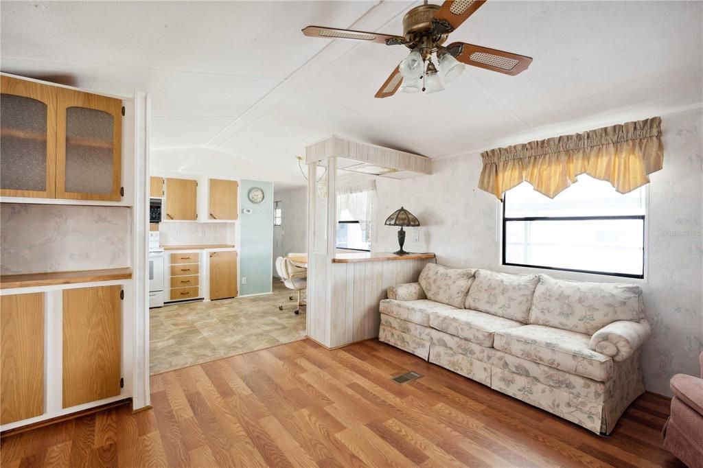 Living room has laminate flooring and ceiling fan.