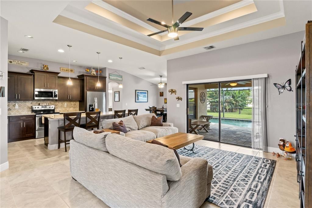 Living rom with ceiling fan, a raised ceiling, and ornamental molding