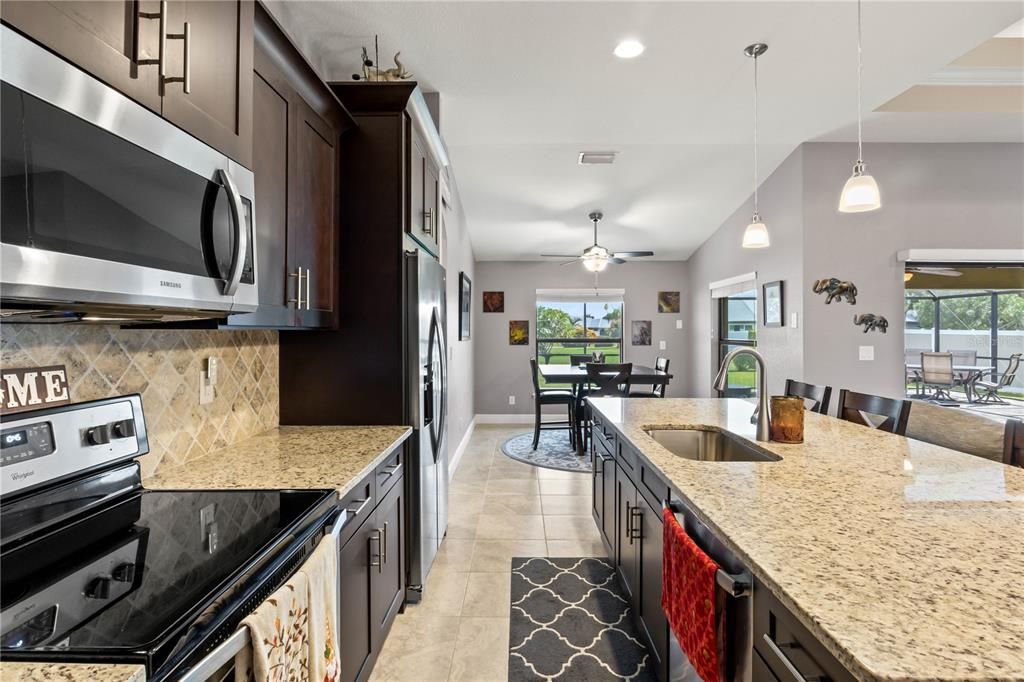 Kitchen with light stone counters, appliances with stainless steel finishes, sink, and ceiling fan