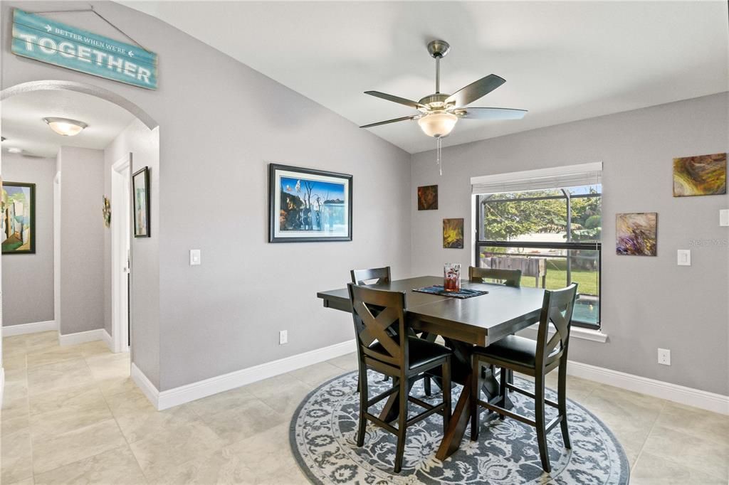 Tiled dining area with ceiling fan and lofted ceiling