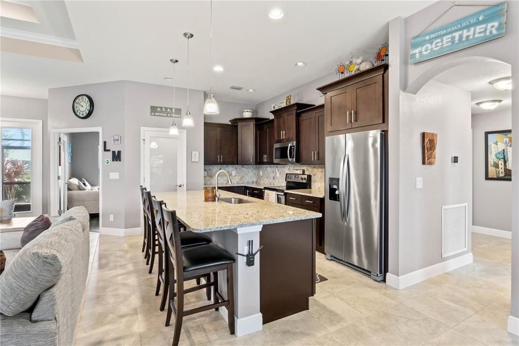 Kitchen featuring light stone counters, pendant lighting, sink, dark brown cabinets, and appliances with stainless steel finishes