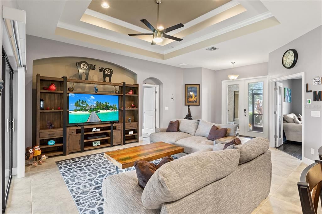 Tiled living room featuring ornamental molding, a tray ceiling, and ceiling fan