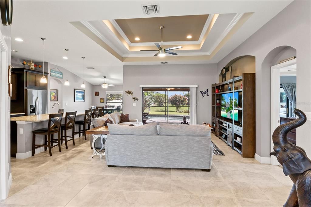 Living room with crown molding, a tray ceiling, and ceiling fan