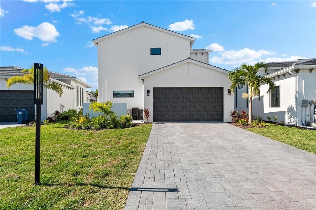 Rear of home showing two car garage, which has speckled epoxy flooring, and long driveway.