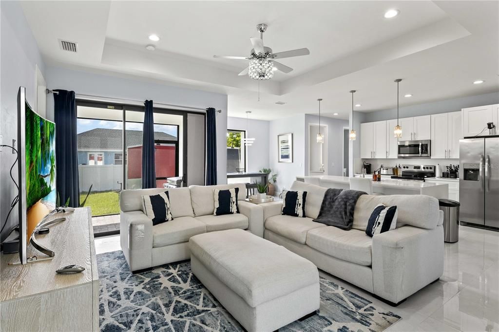 Living room with ceiling fan and a tray ceiling