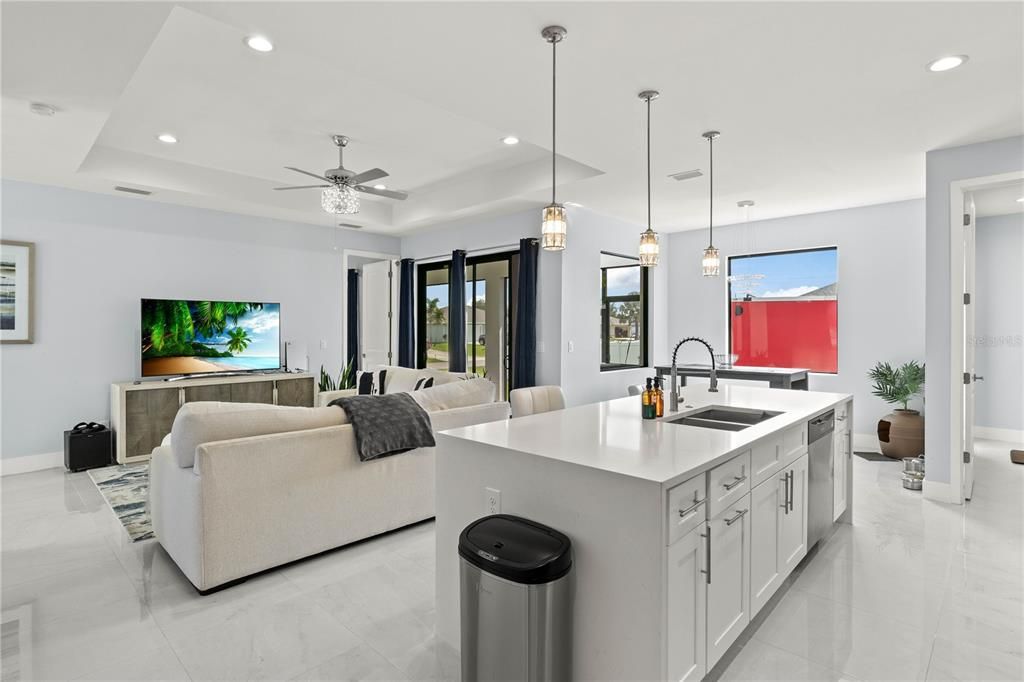 Kitchen featuring plenty of natural light, white cabinets, a kitchen island with sink, and sink